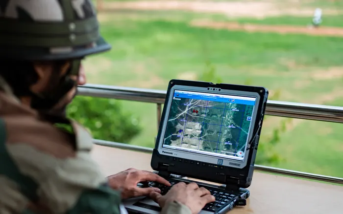 An operator at a ruggedised field laptop showing a mapping display.